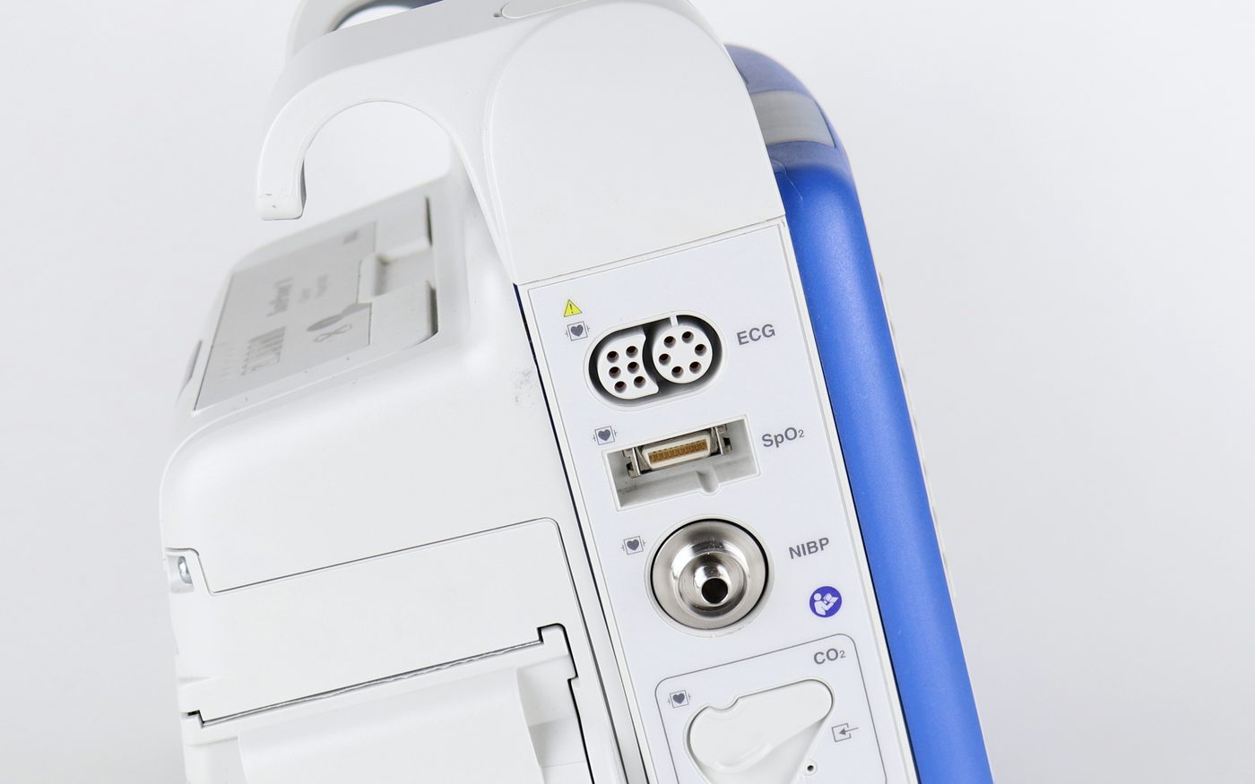 A close view of the side of the monitor: its printer door and a panel of labelled patient-cable ports — ECG, SpO2, NIBP and CO2 — with a latch above them.